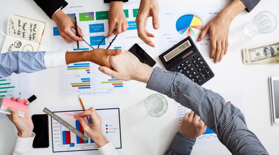 Picture of businessmen's hands on white table with documents, coffee and drafts